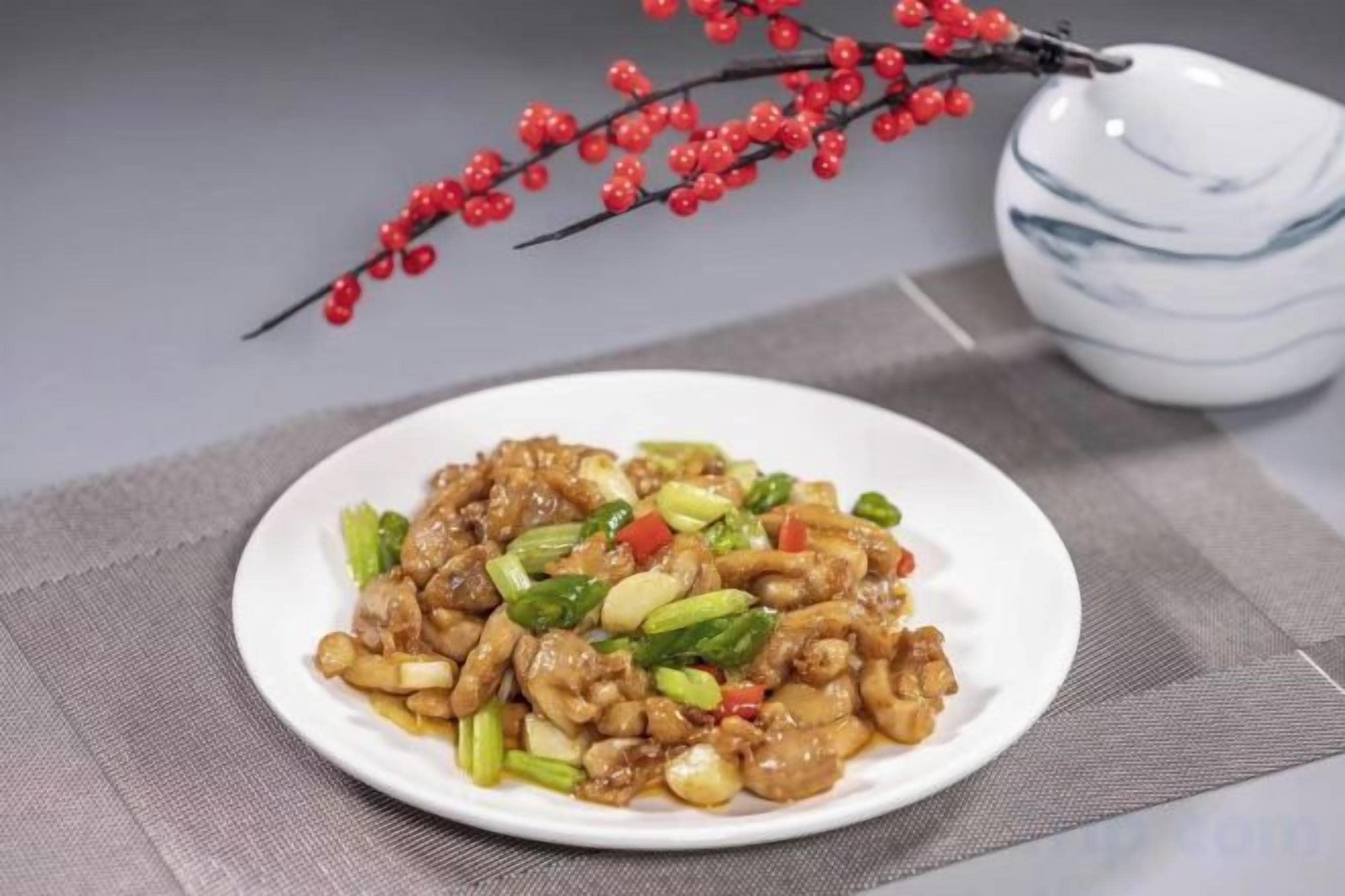 A plate of stir-fried chicken with vegetables on a white plate.