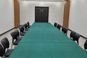 A conference room with a long table and chairs, a door at the end, and a textured wall. - Mingdu Hotel (Wuyang)