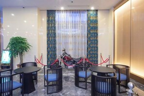 A hotel room with a dining area featuring round tables and chairs, a potted plant, and a red motorcycle parked outside. - Mingdu Hotel (Wuyang)