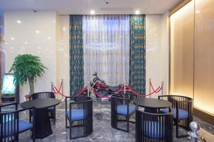 Habitaci ón de hotel con comedor que incluye mesas y sillas redondas, una planta en maceta, y una motocicleta roja estacionada afuera.