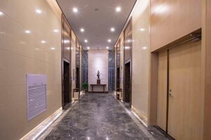 Un pasillo con piso de mármol, puertas de madera e iluminación empotrada.
