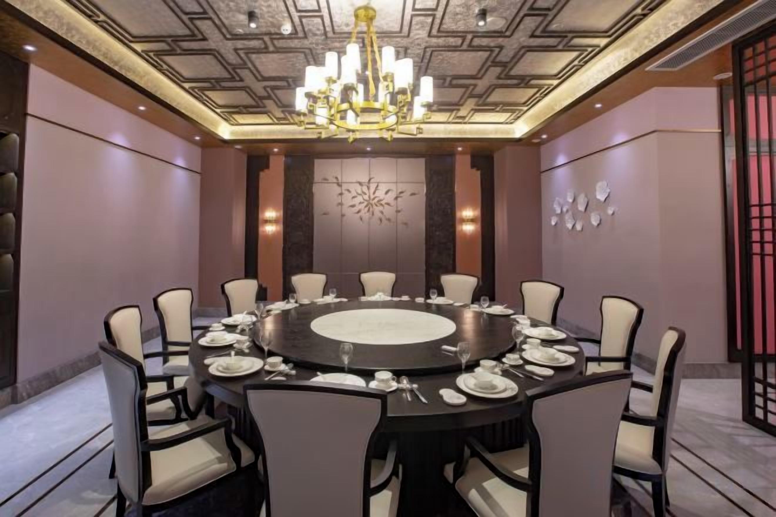 Un salón de conferencias con una mesa redonda, sillas y una araña.