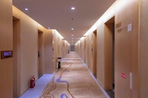 Un pasillo de hotel con puertas numeradas 8617 y 8618, un extintor y un letrero de salida de emergencia roja.
