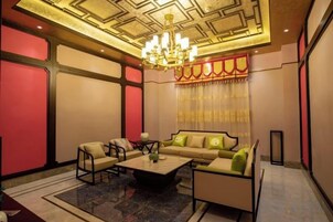 Habitación de hotel con candelabro, sofá y alfombra estampada.