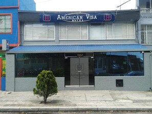 Welcome to the American Visa Hotel, featuring a simple, functional design with a prominent entrance.