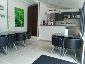 Kitchen area with central island and dining table for four, featuring a microwave, coffee maker, and kettle.