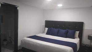 A bedroom with a bed, a nightstand, and a door. - Hotel American Visa Bogota (Bogotá)