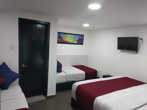 Habitación de hotel con dos camas, un televisor y un cuadro en la pared.