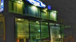 A hotel with a prominent American Visa sign and a logo on the windows. - Hotel American Visa Bogota (Bogotá)