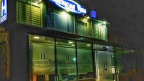 A hotel with a prominent American Visa sign and a logo on the windows. - Hotel American Visa Bogota (Bogotá)