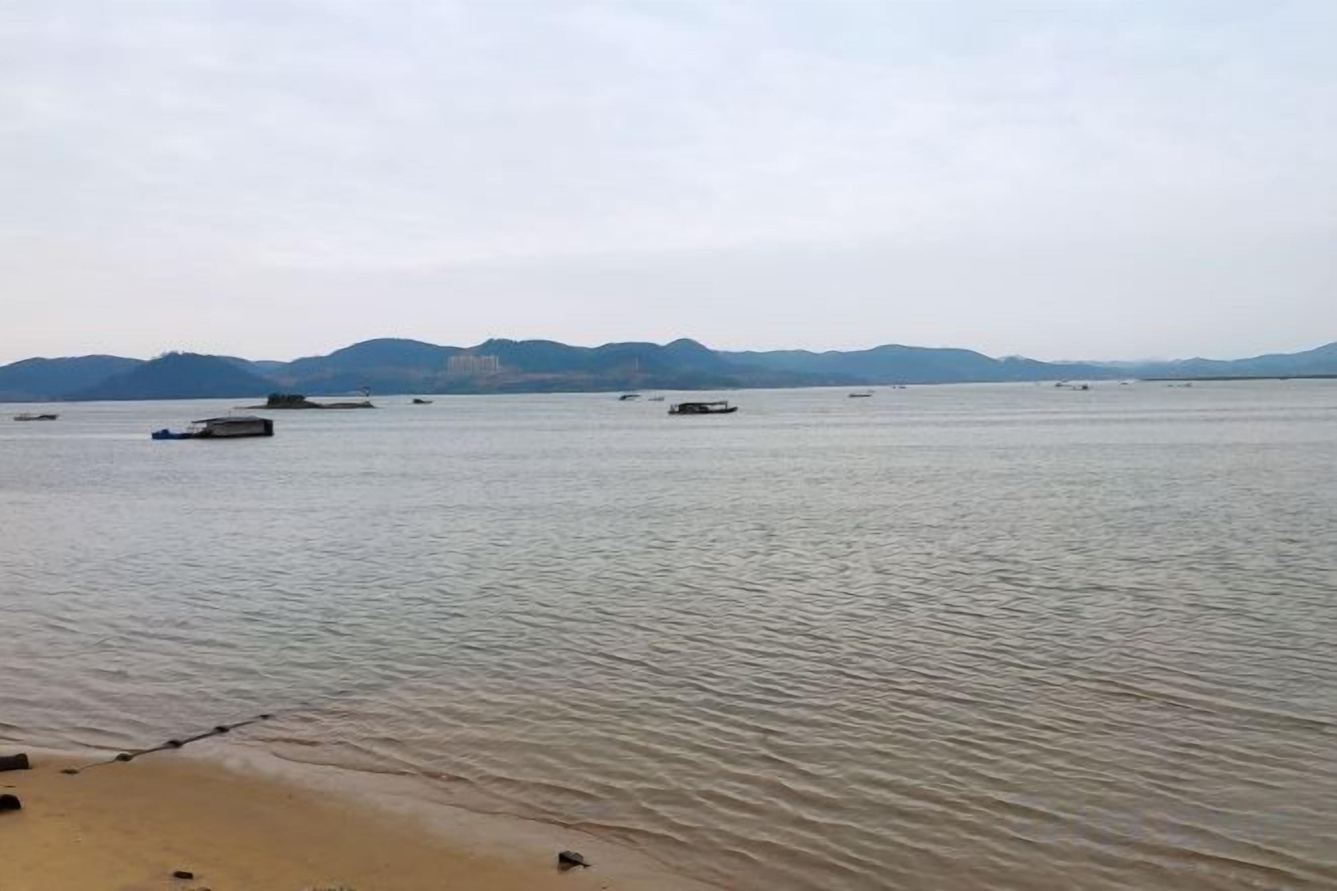 A calm body of water with boats and distant mountains.