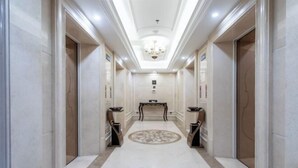 A hallway with marble flooring, a central console table, and a chandelier.