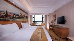 A hotel room with two beds, a desk, a television, and a painting on the wall.