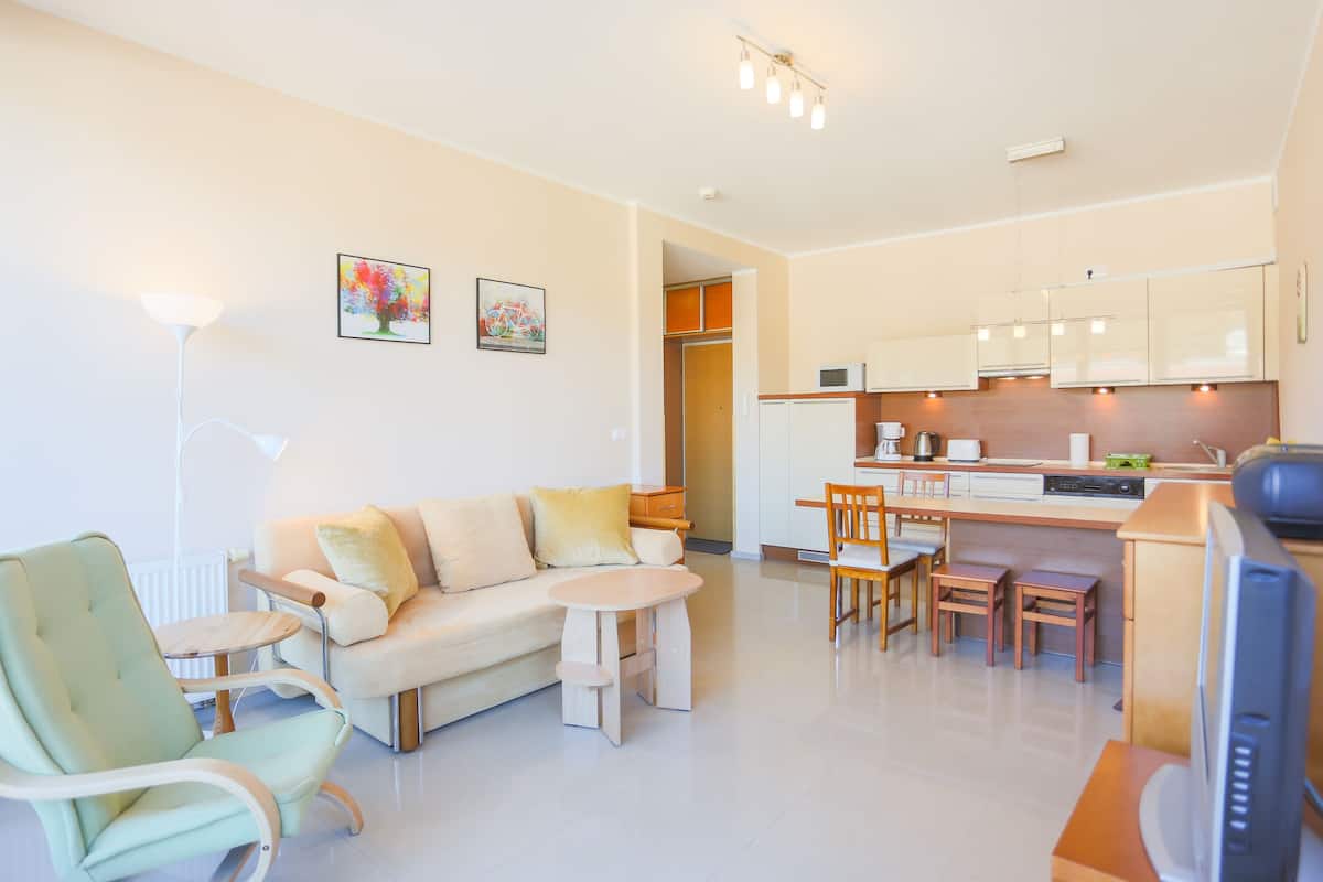 A modern living room with a sofa, chairs, a small table, and a television.