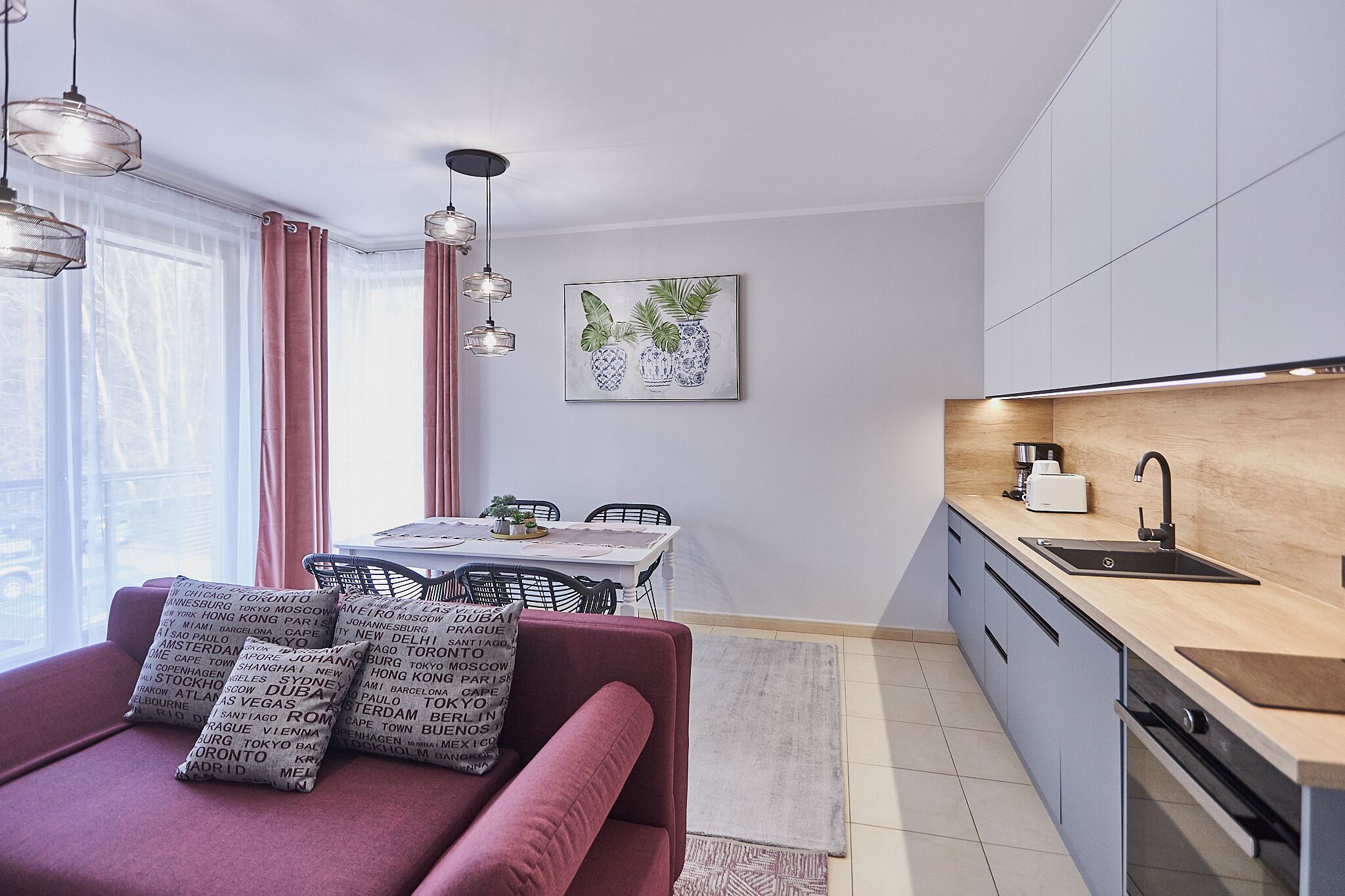 A modern kitchen with a wooden countertop, a sink, and a dining area with a table and chairs.