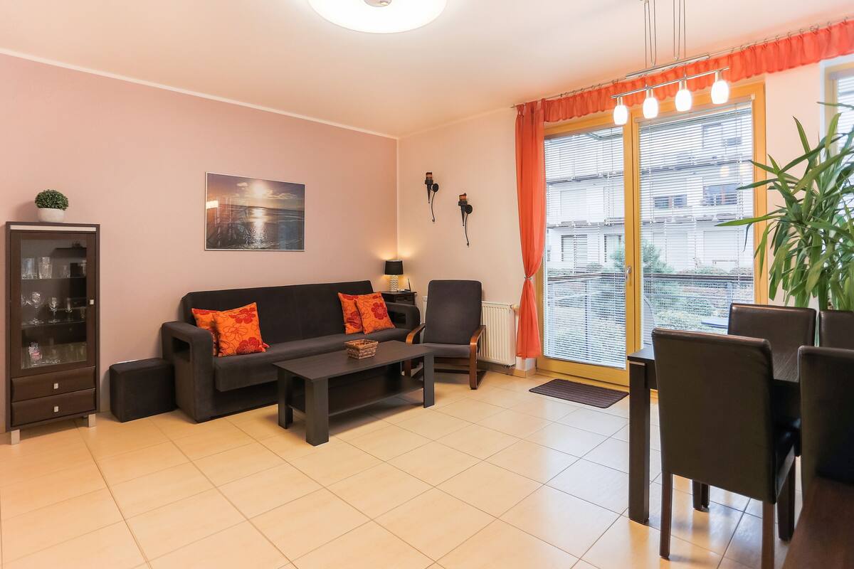 A living room with a sofa, coffee table, and a dining area with chairs and a table.