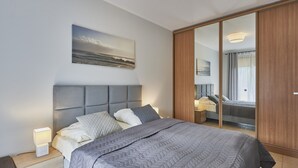 Un dormitorio moderno con una cama grande, cabecera, lámparas de noche, un cuadro y un armario.