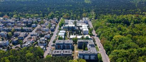 An aerial view of a residential area with houses, roads, and a dense forest in the background.