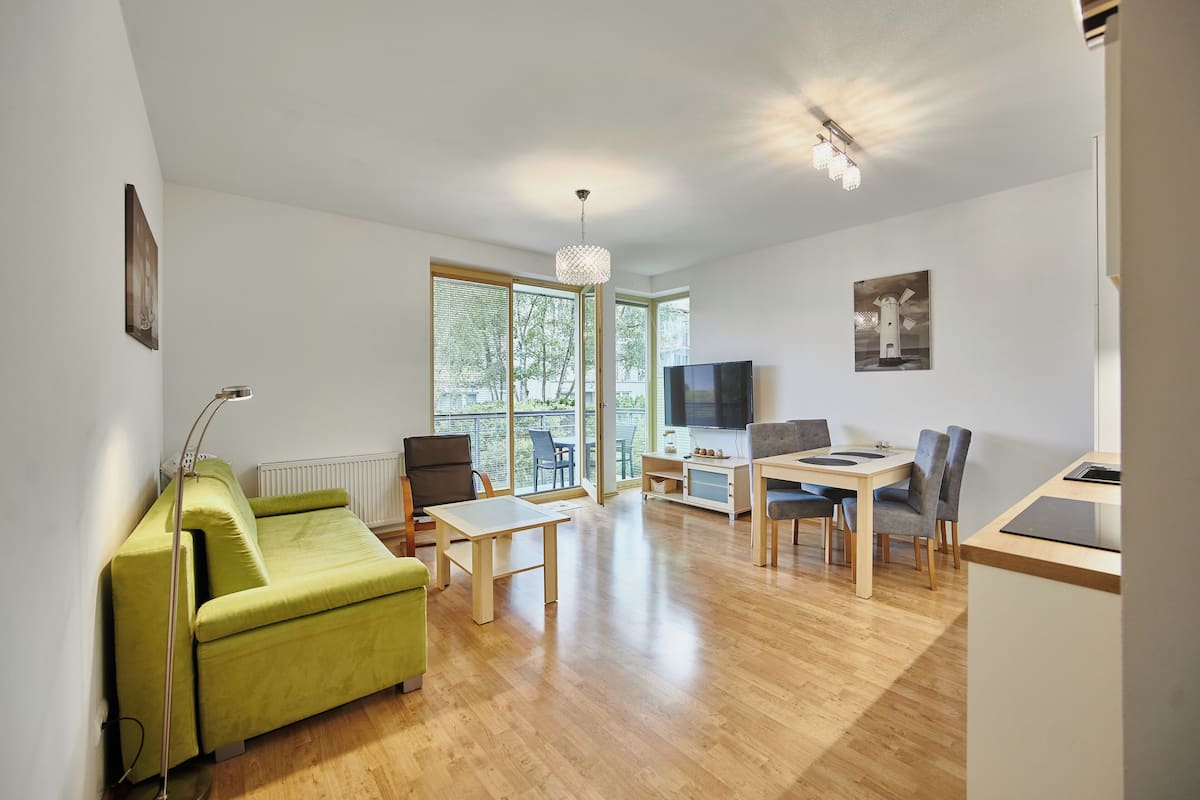 A modern living room with a green sofa, a dining table, and a TV.