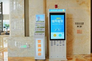A hotel reception area with a digital kiosk and a vertical information stand. - Expo Hotel (Tongxiang)