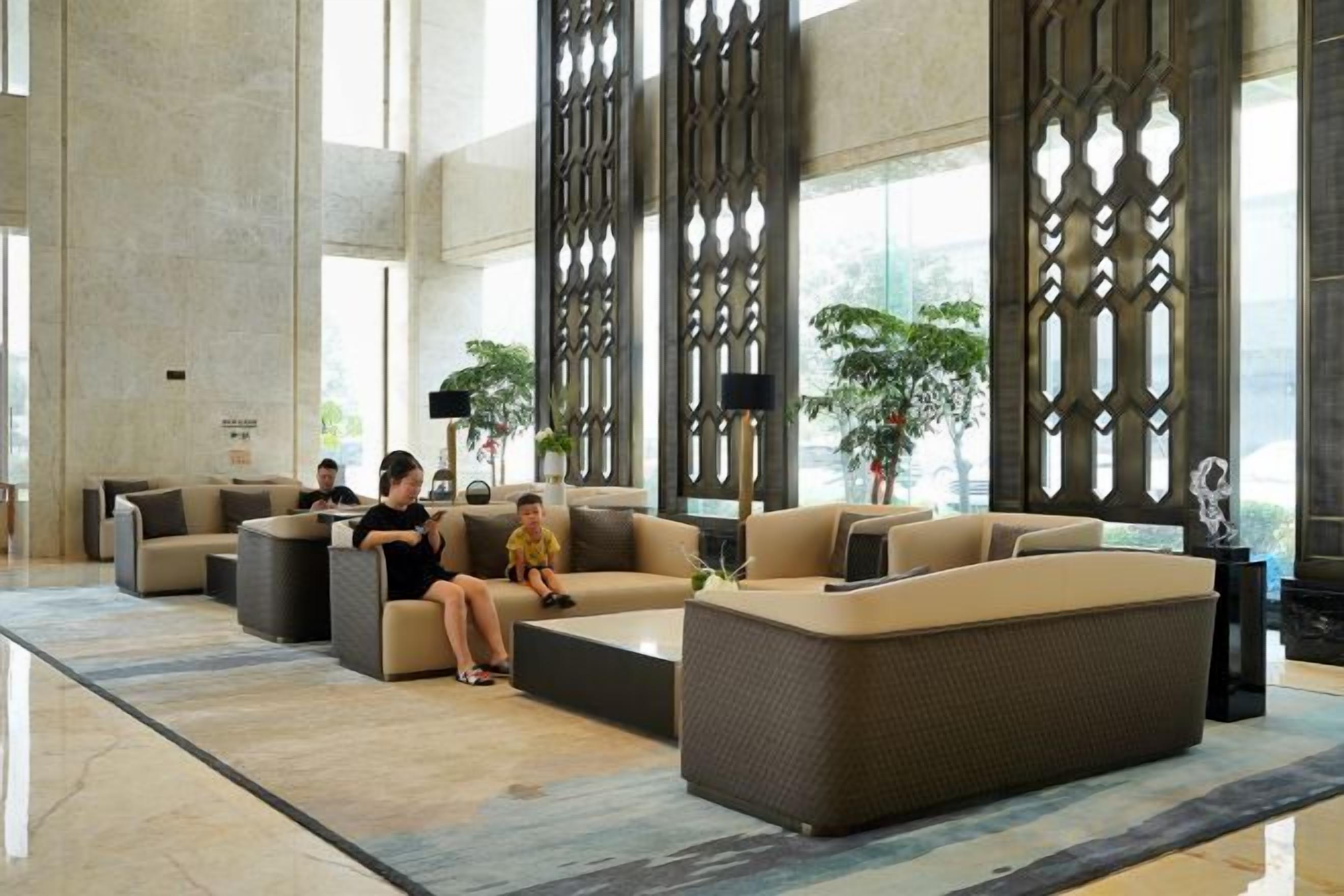 Un vestíbulo amplio con sofás modernos, una mesa de centro y paneles decorativos.