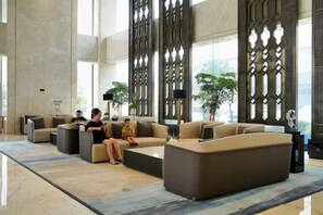 A spacious lobby with modern sofas, a coffee table, and decorative screens. - Expo Hotel (Tongxiang)