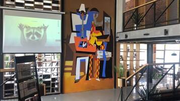 A modern interior with a large abstract mural, a projection screen, and a staircase.