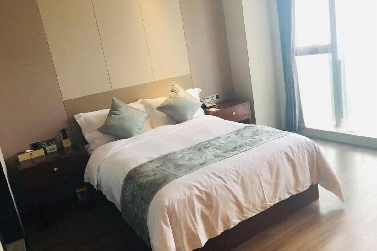 Una habitación de hotel con cama, mesitas de noche y ventana.