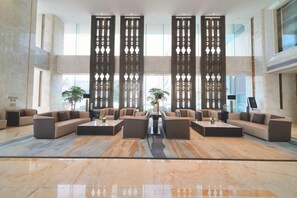 A spacious lobby with a central seating area, large windows, and decorative vertical panels. - Expo Hotel (Tongxiang)