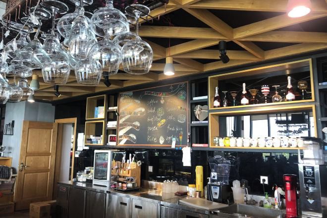 A bar area with a chalkboard menu, shelves with bottles, and a coffee machine.