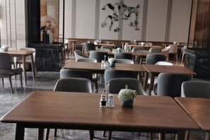 A restaurant with multiple tables and chairs, a marble counter, and wall art. - Expo Hotel (Tongxiang)