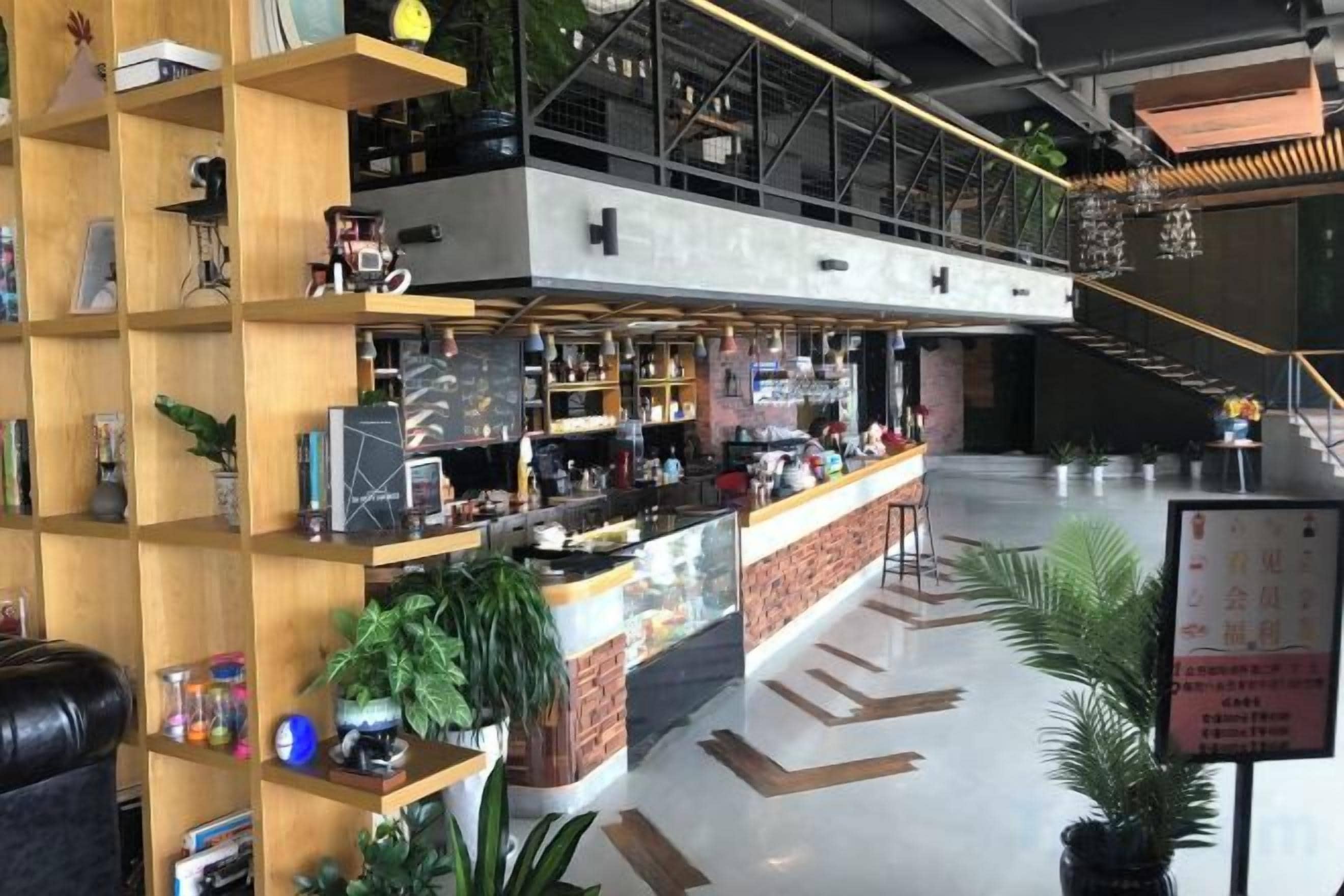 A modern bar area with a counter, shelves with various items, and a staircase leading to an upper level.