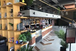 A modern bar area with a counter, shelves with various items, and a staircase leading to an upper level. - Expo Hotel (Tongxiang)