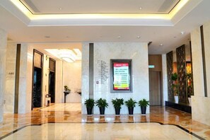 A hotel lobby with a reception desk, a digital directory, and potted plants. - Expo Hotel (Tongxiang)