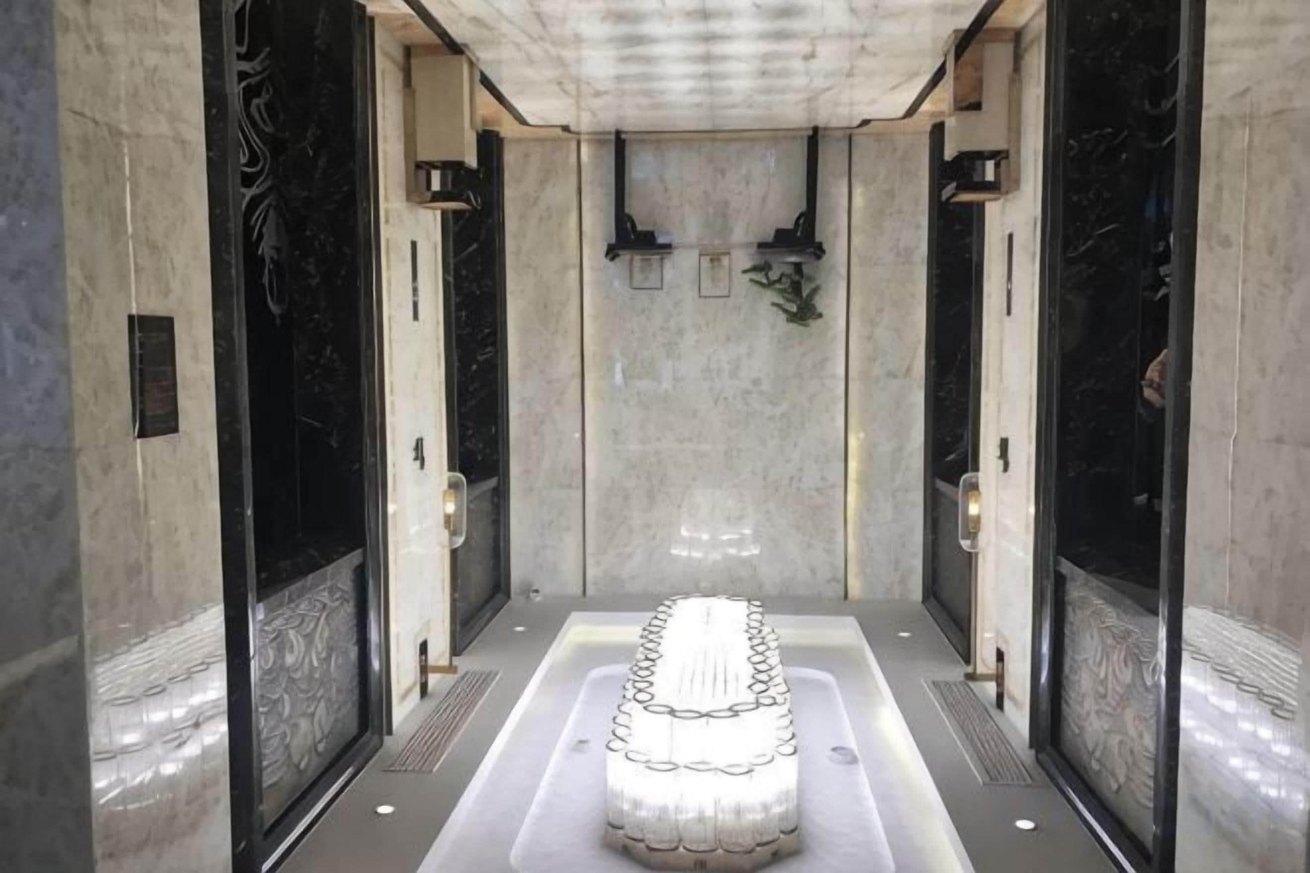 A spa area with a central hot tub, marble walls, and a tiled floor.