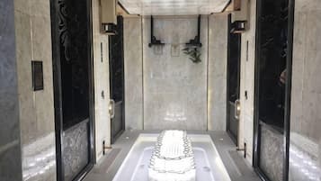 A spa area with a central hot tub, marble walls, and a tiled floor.