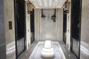 A spa area with a central hot tub, marble walls, and a tiled floor. - Expo Hotel (Tongxiang)