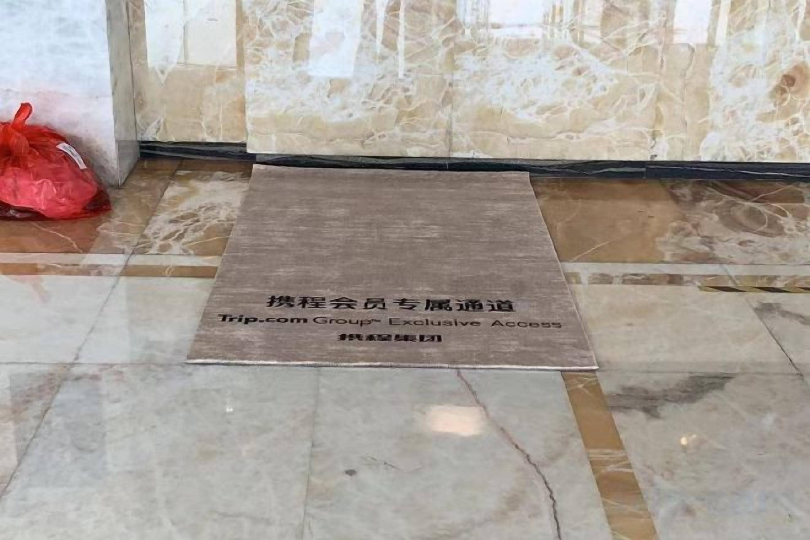 Un tapis avec un texte indiquant qu’il s’agit d’une zone d’accès réservée aux clients des hôtels du groupe Trip.com.