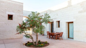 A courtyard with a dining table and chairs, surrounded by a white brick building. - Once Upon a Time in Masseria Sitamara (Lecce)