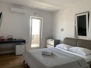 A bedroom with a bed, bedside tables, a desk, a chair, and a window.
