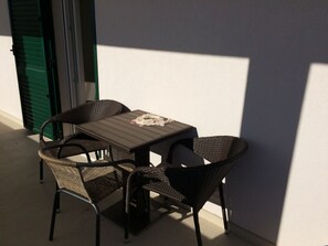 A small outdoor table with two wicker chairs, a green door in the background, and a white wall. - Imotski Blaue See Apartments , Pool (Imotski)