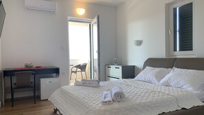Een keurig opgemaakt slaapkamer met een bed, nachtkastjes, een bureau en een stoel.