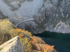 A winding road along a rocky cliffside with a body of water below. - "imotski Blaue See Apartments , Pool" (Imotski)