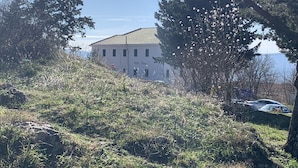 A building with a tiled roof and multiple windows, surrounded by trees and grass. - "imotski Blaue See Apartments , Pool" (Imotski)