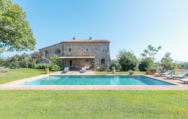 A stone building with a swimming pool, outdoor seating, and a well-maintained lawn. - Casa del Piano Valle dei Calanchi in Front of Civita Di Bagnoregio (Bagnoregio)