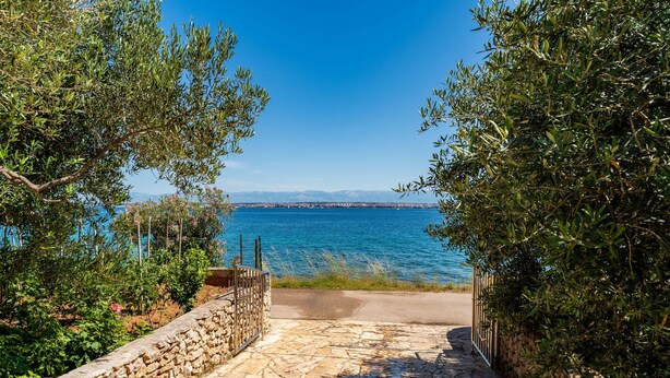 A stone pathway leading to a coastal view with a clear sky and distant mountains. - Apartment by the sea and With Beautiful View, 2 Bedrooms, 4 Persons (Kali)