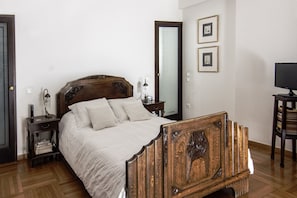 A bedroom with a wooden bed, bedside tables, a mirror, and a television. - The Magnolia - Sophisticated Residence (Athens)
