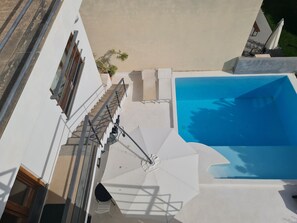 A rooftop pool area with a clear view of the pool, a chair, and a potted plant.