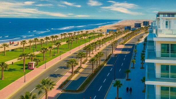 A coastal road lined with palm trees and a modern building with large windows. - 1relax in a Fully Equipped Beachfront Chalet (Al-Manasrah)