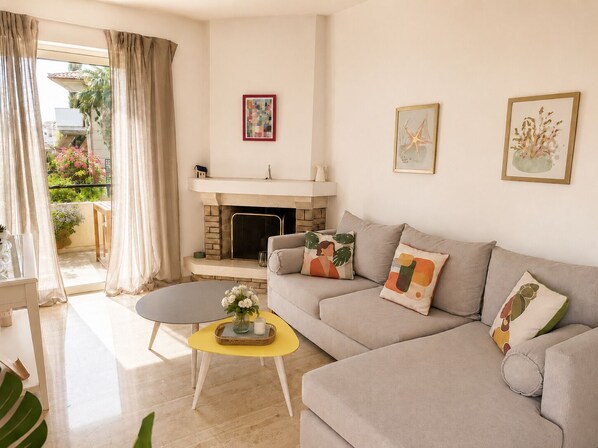 A living room with a sofa, a coffee table, a fireplace, and artwork on the walls.